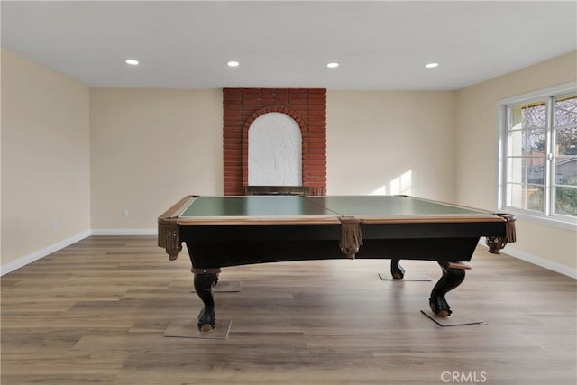 recreation room featuring a brick fireplace and light hardwood / wood-style floors