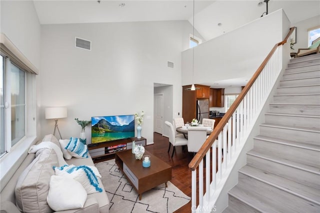 living room featuring high vaulted ceiling and light hardwood / wood-style flooring