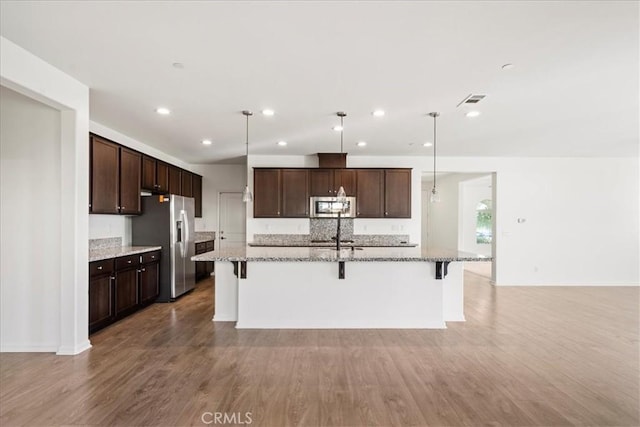 kitchen featuring a breakfast bar, appliances with stainless steel finishes, a center island with sink, and hanging light fixtures