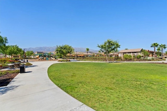 view of property's community featuring a playground, a mountain view, and a lawn