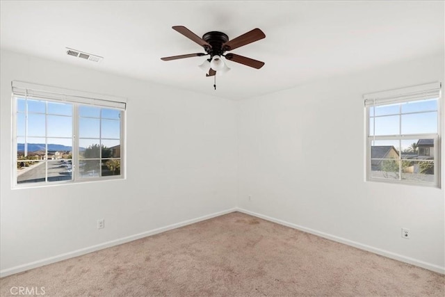 carpeted empty room featuring ceiling fan and a wealth of natural light