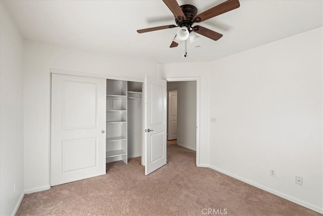 unfurnished bedroom featuring ceiling fan, light colored carpet, and a closet