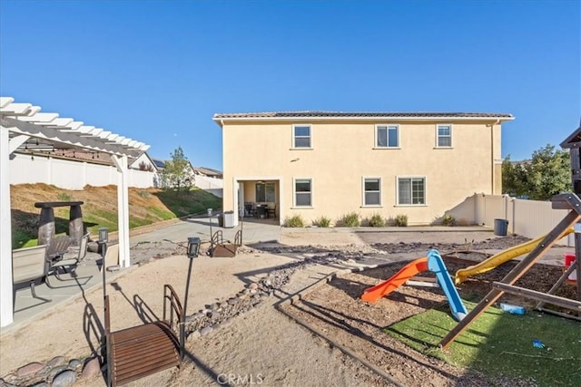 rear view of property featuring a playground and a patio area