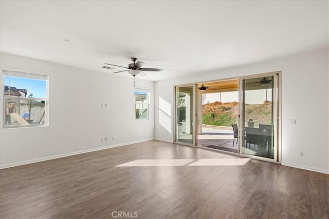 empty room featuring ceiling fan, plenty of natural light, and dark hardwood / wood-style flooring