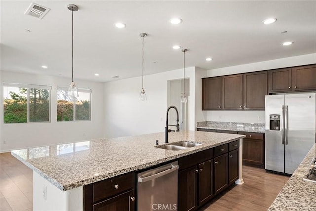 kitchen with light stone countertops, sink, pendant lighting, and stainless steel appliances