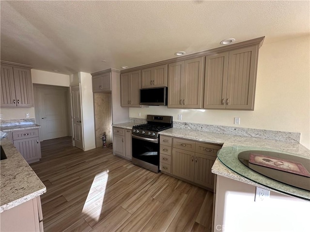 kitchen with light stone countertops, a textured ceiling, and gas stove