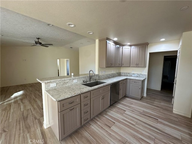 kitchen featuring kitchen peninsula, lofted ceiling, stainless steel dishwasher, light stone counters, and sink