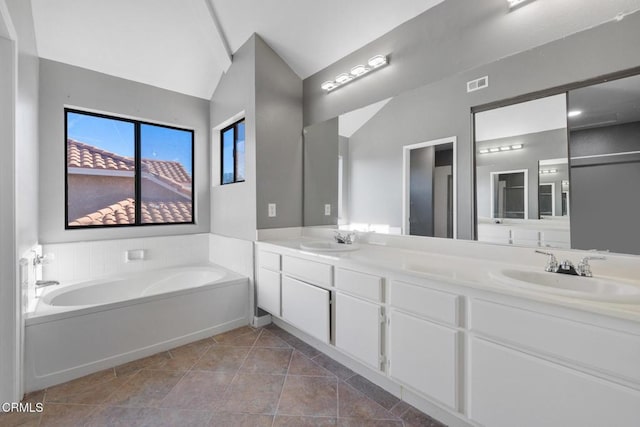 bathroom with tile patterned floors, a bath, vanity, and vaulted ceiling