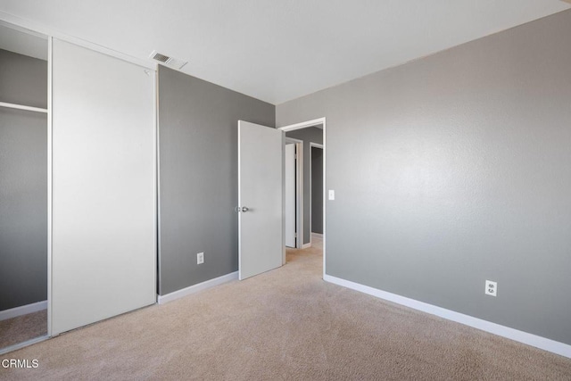 unfurnished bedroom with a closet and light carpet