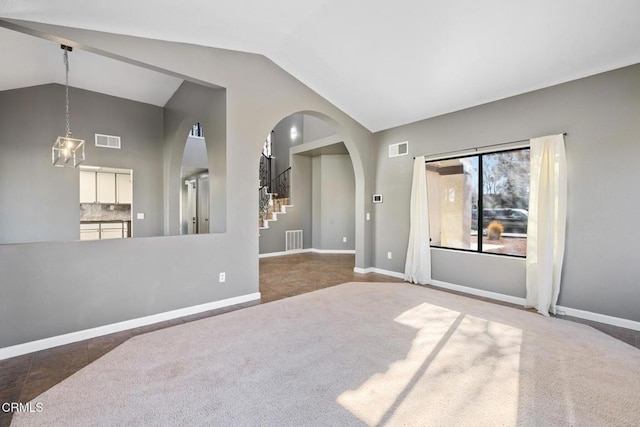 spare room featuring dark colored carpet and high vaulted ceiling