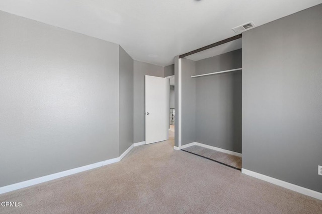 unfurnished bedroom featuring a closet and light colored carpet