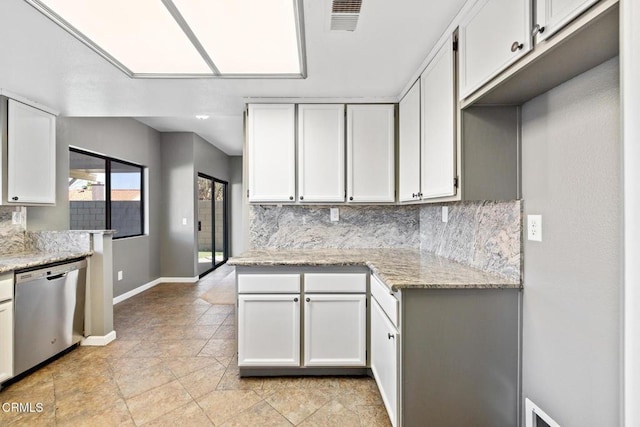 kitchen with stainless steel dishwasher, white cabinets, light stone counters, and tasteful backsplash