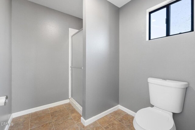 bathroom with toilet, tile patterned flooring, and walk in shower