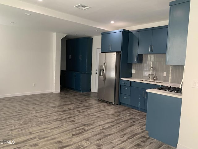 kitchen with stainless steel refrigerator with ice dispenser, dark wood-type flooring, blue cabinetry, and sink