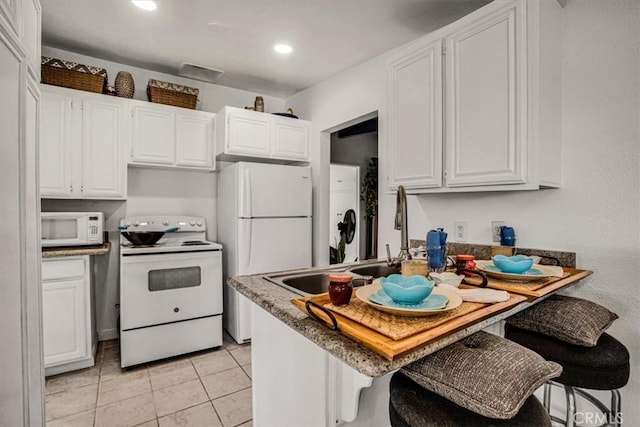 kitchen featuring light tile patterned flooring, a kitchen breakfast bar, white cabinetry, and white appliances