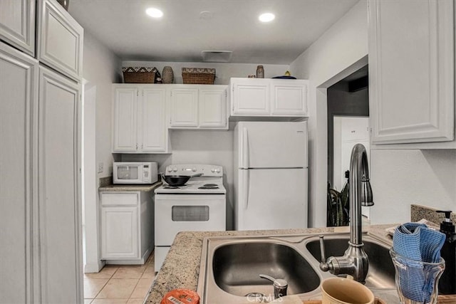 kitchen with light stone counters, light tile patterned flooring, white appliances, and white cabinetry