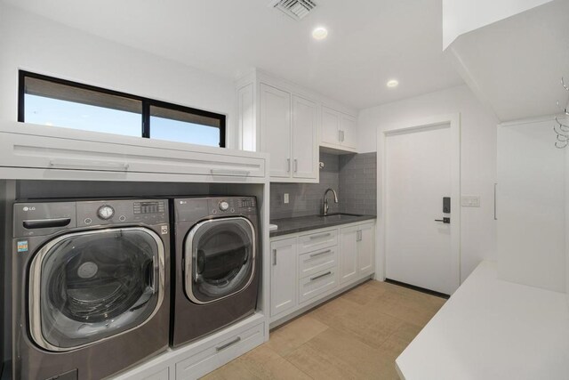 laundry area featuring washing machine and dryer, sink, and cabinets