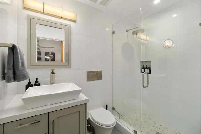 bathroom with a shower with door, vanity, tasteful backsplash, tile walls, and toilet