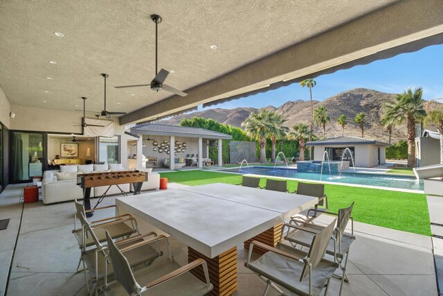 view of patio with pool water feature, ceiling fan, exterior bar, and a mountain view