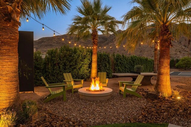 patio terrace at dusk featuring a mountain view and an outdoor fire pit