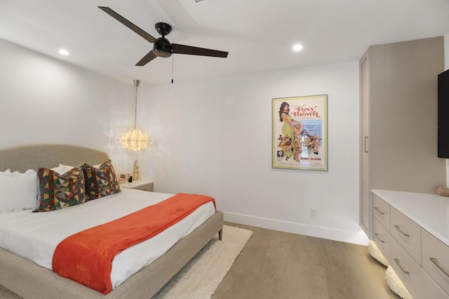 bedroom featuring ceiling fan with notable chandelier and dark wood-type flooring