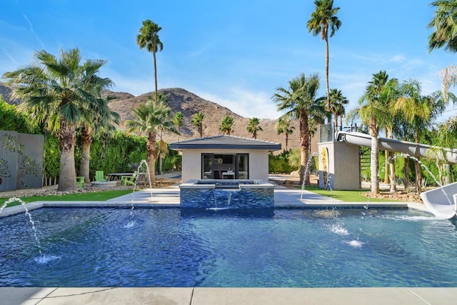 view of pool with pool water feature, a mountain view, and an in ground hot tub