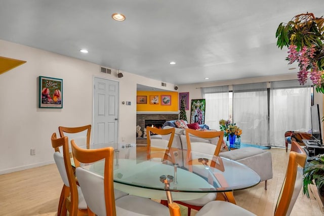 dining space featuring light hardwood / wood-style floors and a stone fireplace