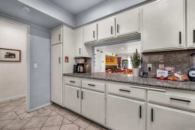 kitchen featuring light tile patterned floors, backsplash, and white cabinets