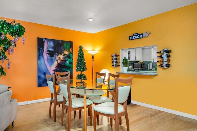 dining room with light wood finished floors, recessed lighting, and baseboards