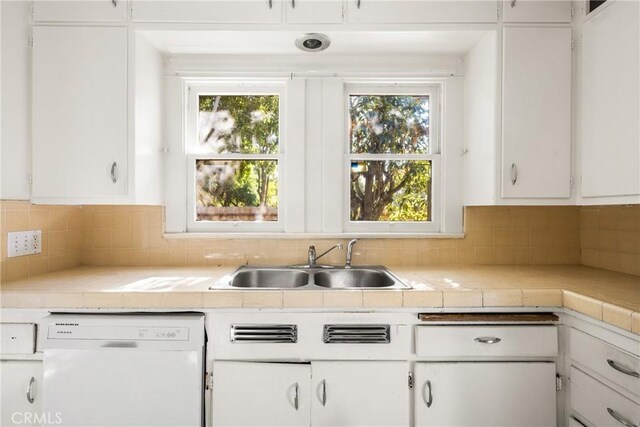 kitchen with sink, backsplash, white cabinets, and dishwasher