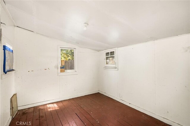 unfurnished room with dark hardwood / wood-style floors and vaulted ceiling