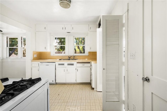 kitchen with white appliances, white cabinetry, sink, backsplash, and plenty of natural light