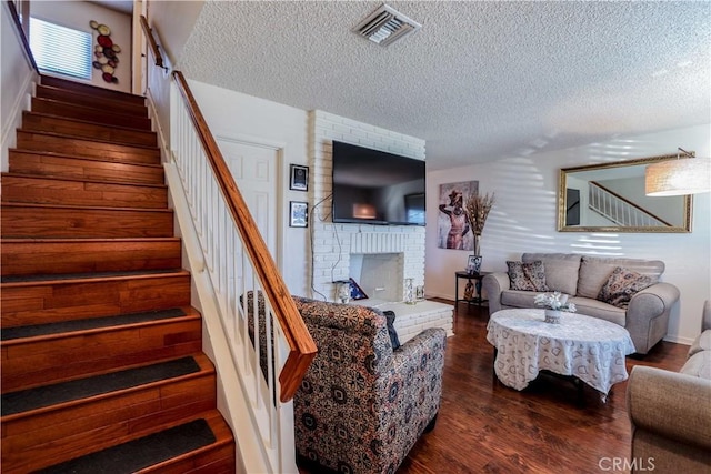 living room featuring a fireplace, dark hardwood / wood-style flooring, and a textured ceiling