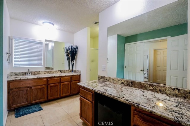 bathroom featuring a textured ceiling, tile patterned floors, and vanity