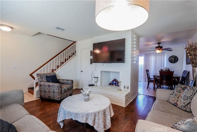 living room featuring a textured ceiling, dark wood-type flooring, and ceiling fan