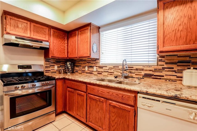 kitchen featuring light stone countertops, dishwasher, sink, stainless steel range with gas cooktop, and light tile patterned floors