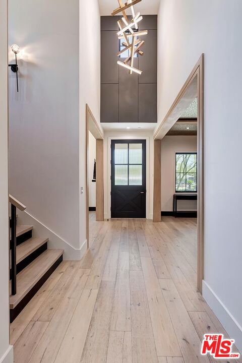 entrance foyer with a high ceiling, a chandelier, and light hardwood / wood-style flooring