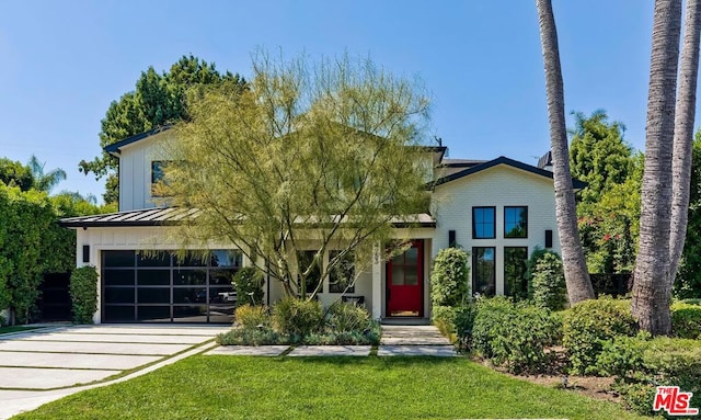 view of property hidden behind natural elements featuring a garage and a front yard