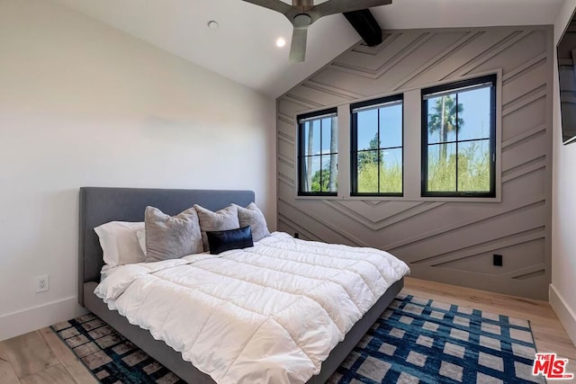 bedroom featuring ceiling fan, light hardwood / wood-style flooring, and lofted ceiling with beams