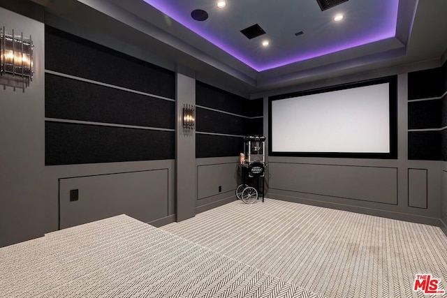 carpeted home theater with a raised ceiling