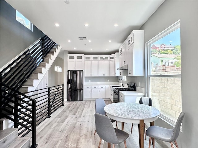 kitchen featuring stainless steel appliances, light hardwood / wood-style flooring, white cabinetry, and sink