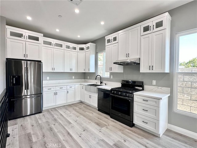 kitchen featuring black appliances, white cabinets, light wood-type flooring, and sink