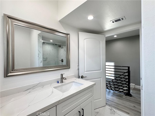 bathroom with a textured ceiling, walk in shower, and vanity