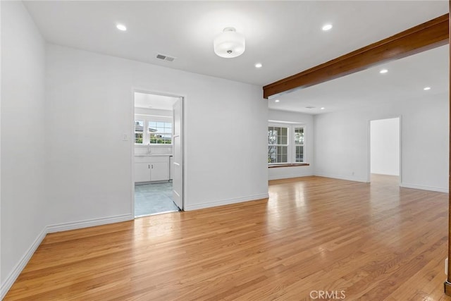 spare room with beamed ceiling and light hardwood / wood-style floors