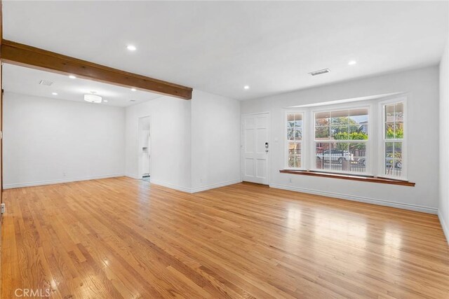 unfurnished living room with light wood-type flooring and beam ceiling