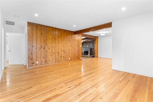 unfurnished living room with wood walls, a fireplace, and light hardwood / wood-style flooring