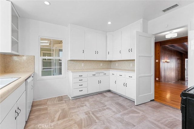 kitchen with white cabinets, black stove, decorative backsplash, and white dishwasher