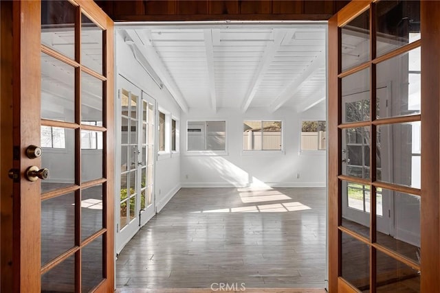 unfurnished sunroom featuring a wealth of natural light, beam ceiling, and french doors