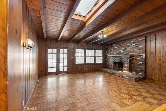 unfurnished living room with a brick fireplace, light parquet flooring, wood walls, and wood ceiling