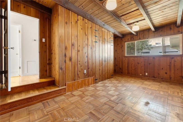 empty room featuring light parquet flooring, beamed ceiling, wooden walls, and wooden ceiling